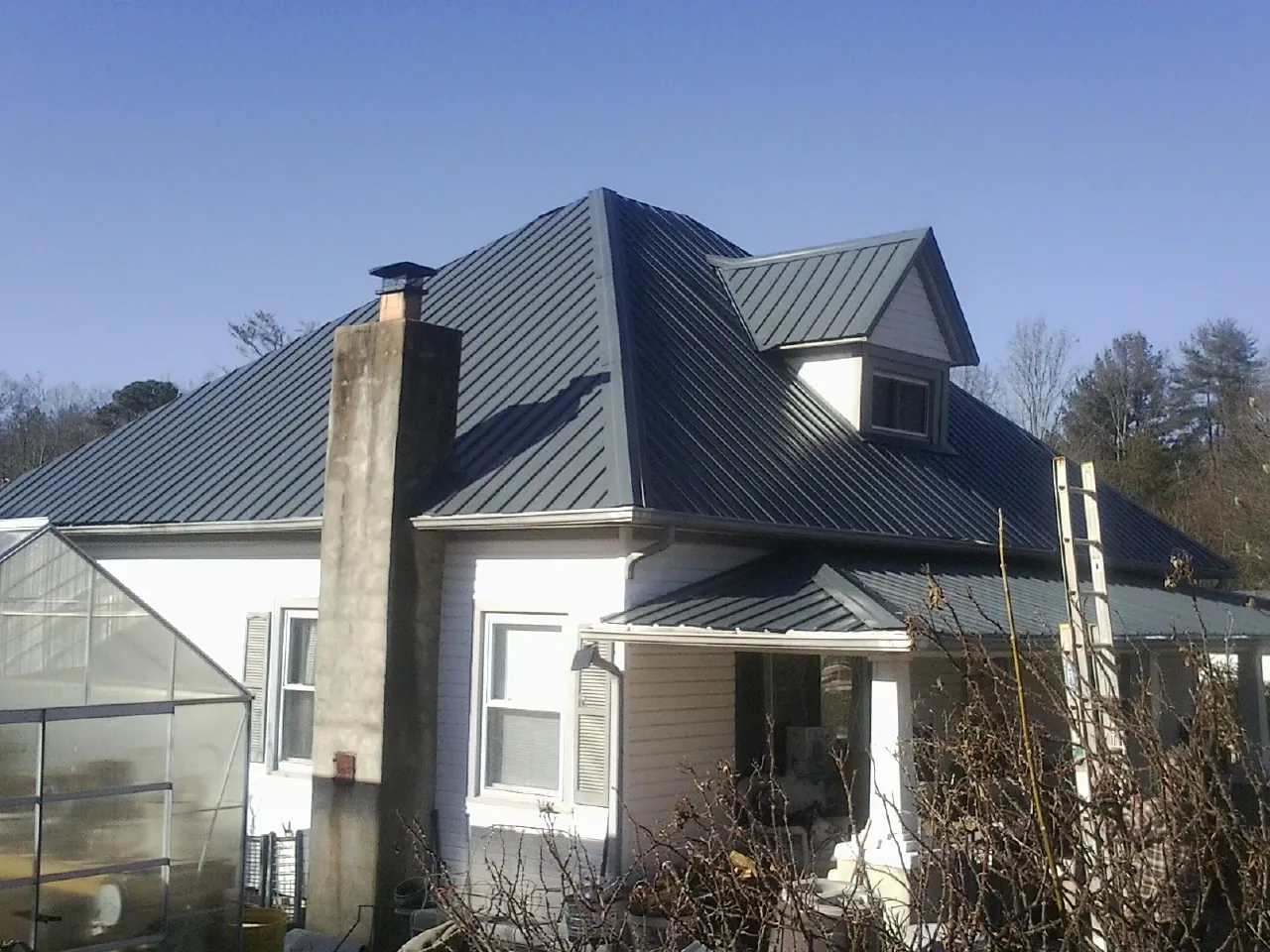 Dark blue standing seam metal roof on a white farmhouse with dormer — Slate & Tile Roof Repair by Roofing Brothers in Chester